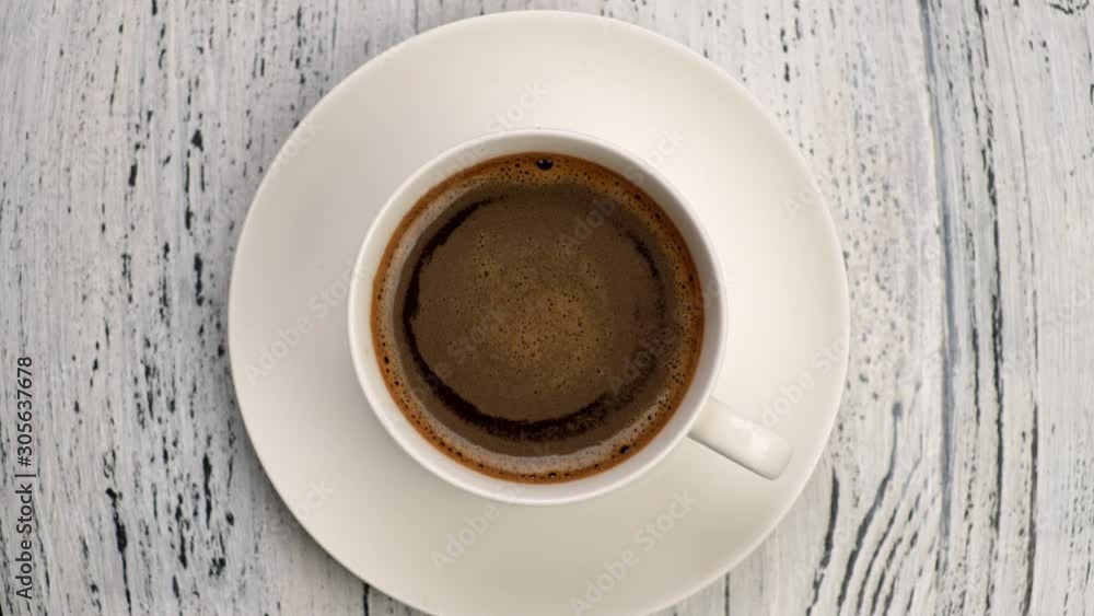 Top down shot of coffee foam swirls in white cup with coffee. Old wooden background, zoom out shot Top down shot of coffee foam swirls in white cup with coffee. Old wooden background, zoom out shot