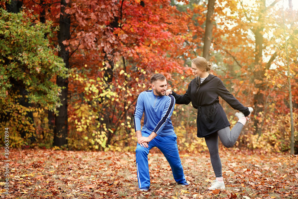 Loving young couple training in autumn park
