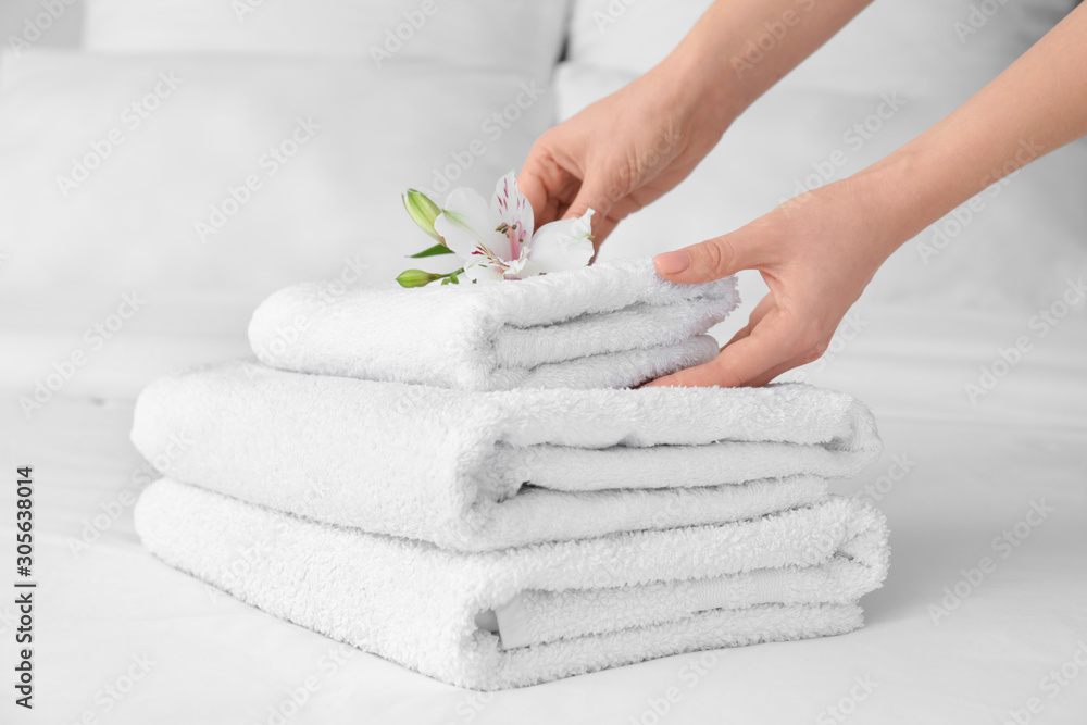 Woman putting flower on stack of clean towels