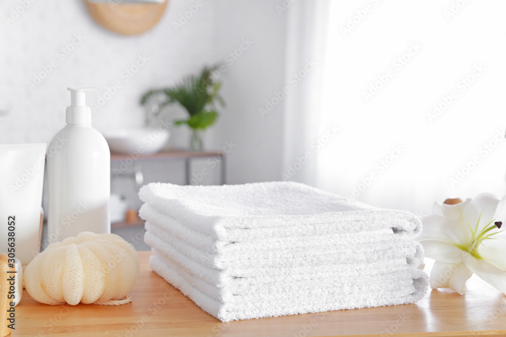 Soft towels and cosmetics on table in bathroom