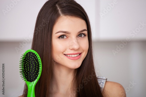 Girl holds a hairbrush without hair and smiling