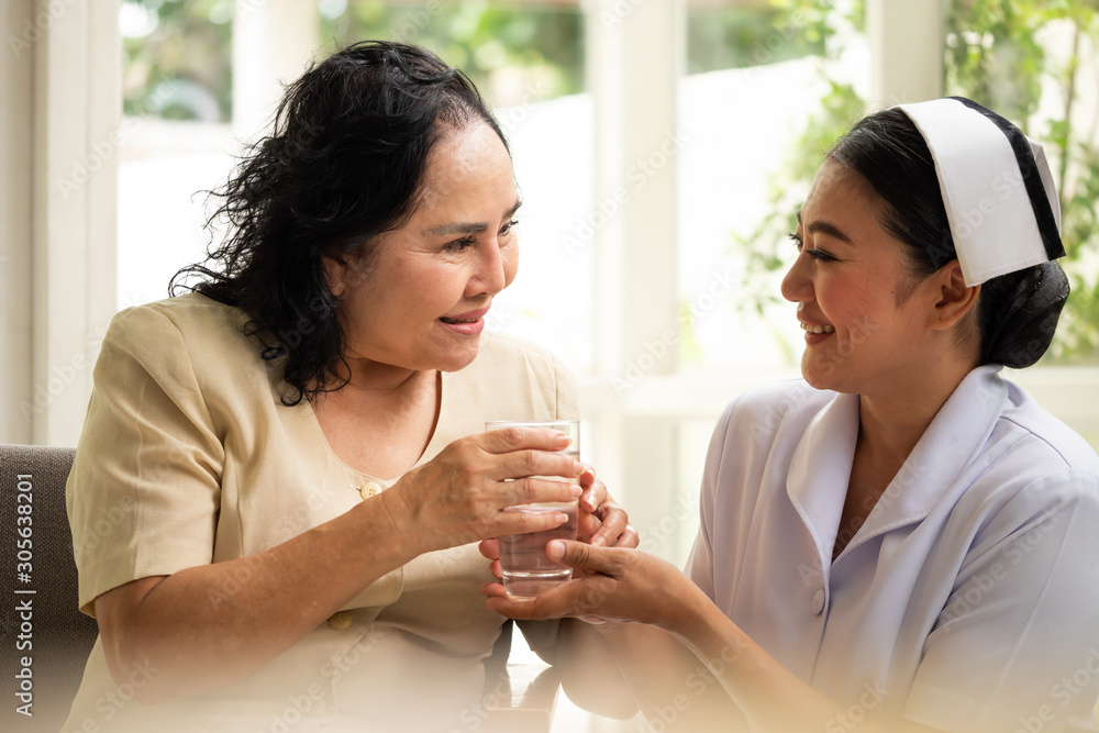Beautiful nurse giving glass of water to female patient who are sitting in the room. Beautiful nurse giving glass of water to female patient who are sitting in the room.