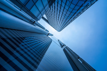 Bottom view of modern skyscrapers in business district against blue sky.