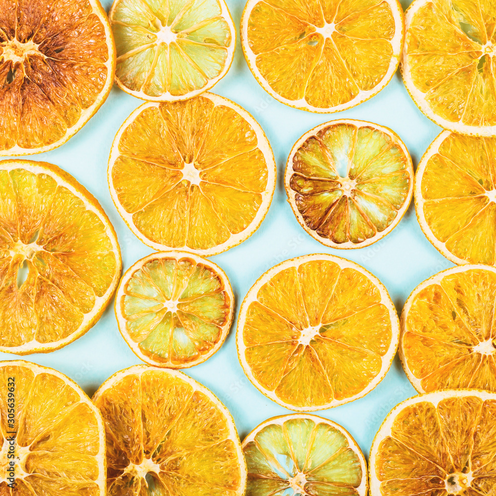 Fototapeta premium Bright colored dried oranges pattern on a blue background. The concept of homemade eco friendly Christmas decorations. Top viiew, flat lay, background.