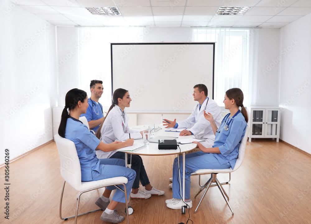 Team of doctors using video projector during conference indoors