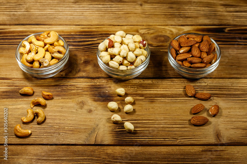 Assortment of nuts on wooden table. Almond, hazelnut and cashew in glass bowls. Healthy eating concept