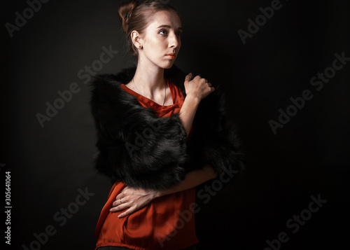 White woman in fur boa on black backdrop 