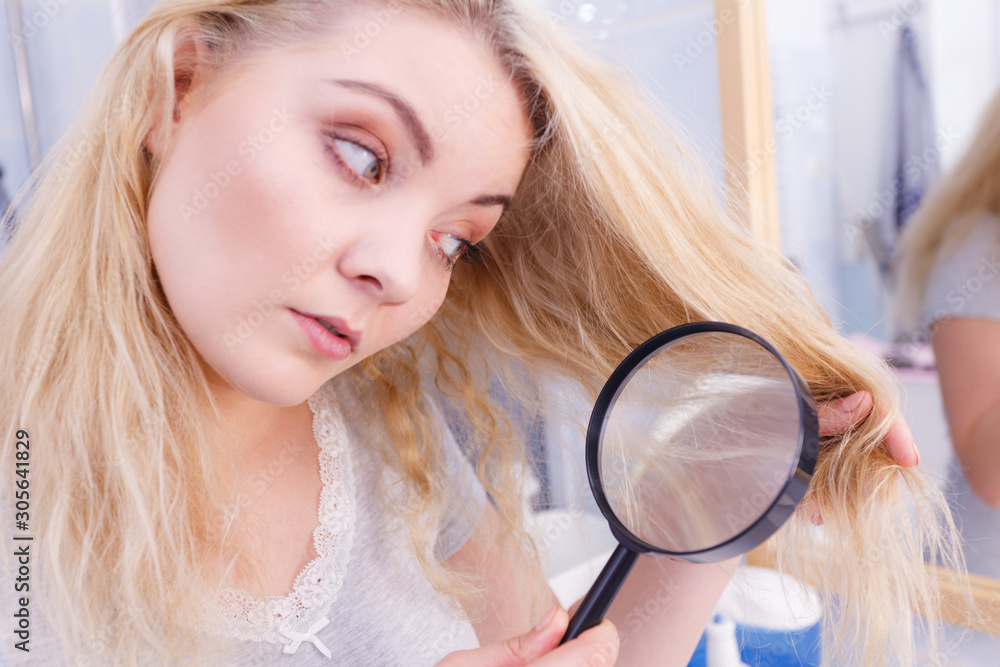 Woman looking at hair ends through magnifying glass Woman looking at hair ends through magnifying glass