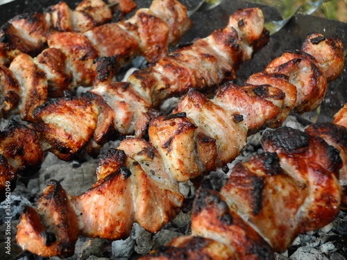 Pork skewers on grill with coals, cooking process