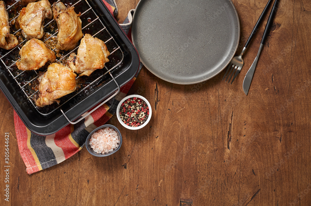 Garlic roast chicken in oven on wooden background