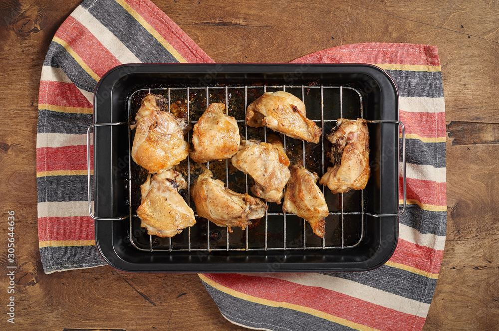 Garlic roast chicken in oven on wooden background