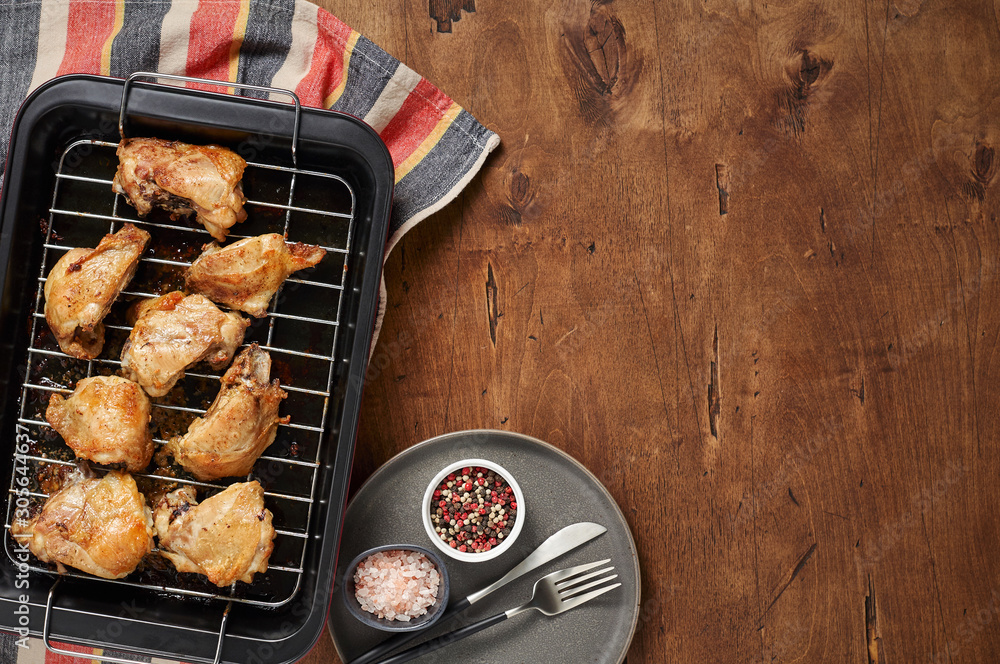 Garlic roast chicken in oven on wooden background