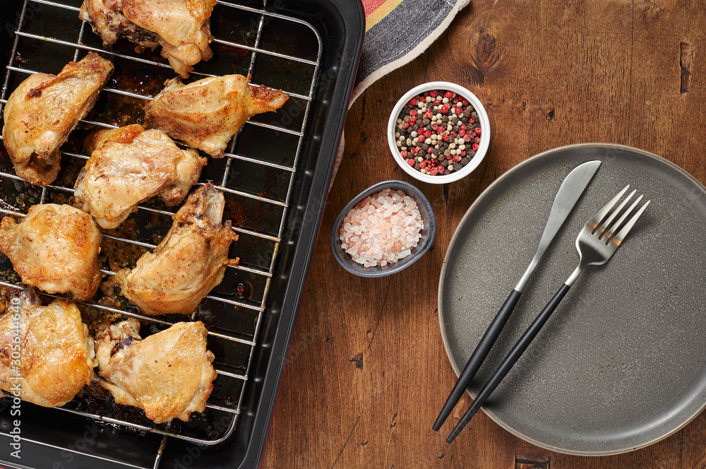 Garlic roast chicken in oven on wooden background