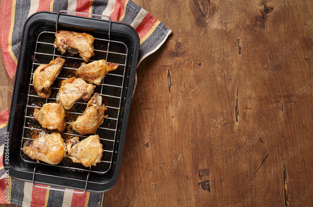 Garlic roast chicken in oven on wooden background