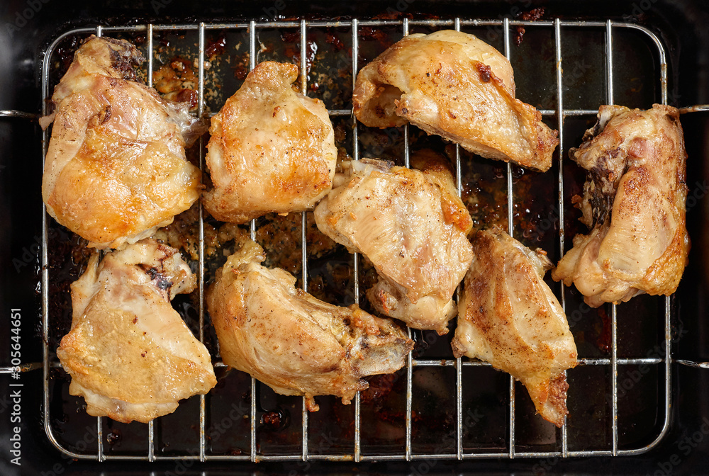 Garlic roast chicken in oven on wooden background