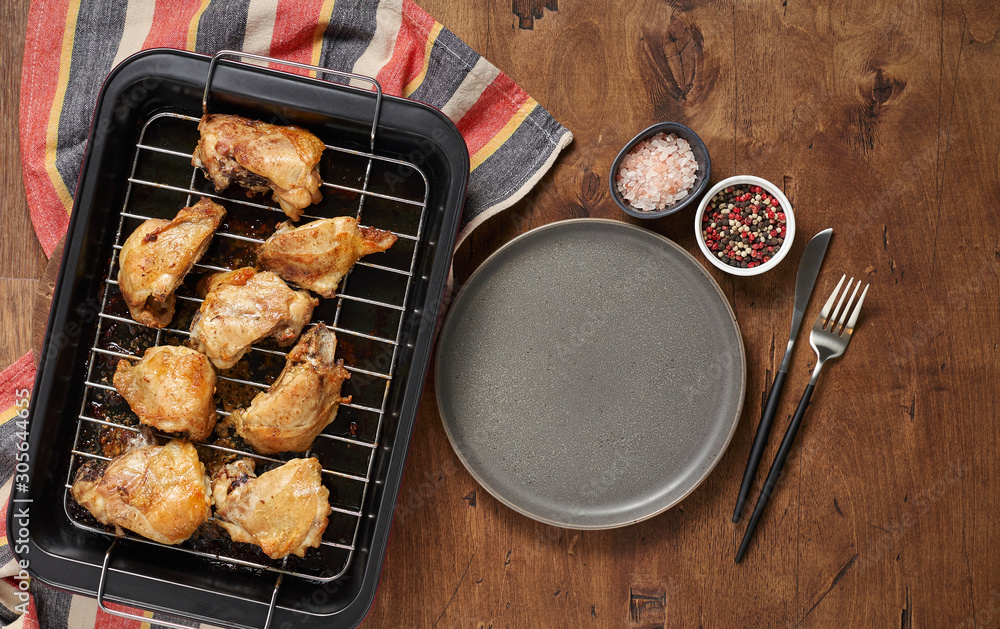 Garlic roast chicken in oven on wooden background