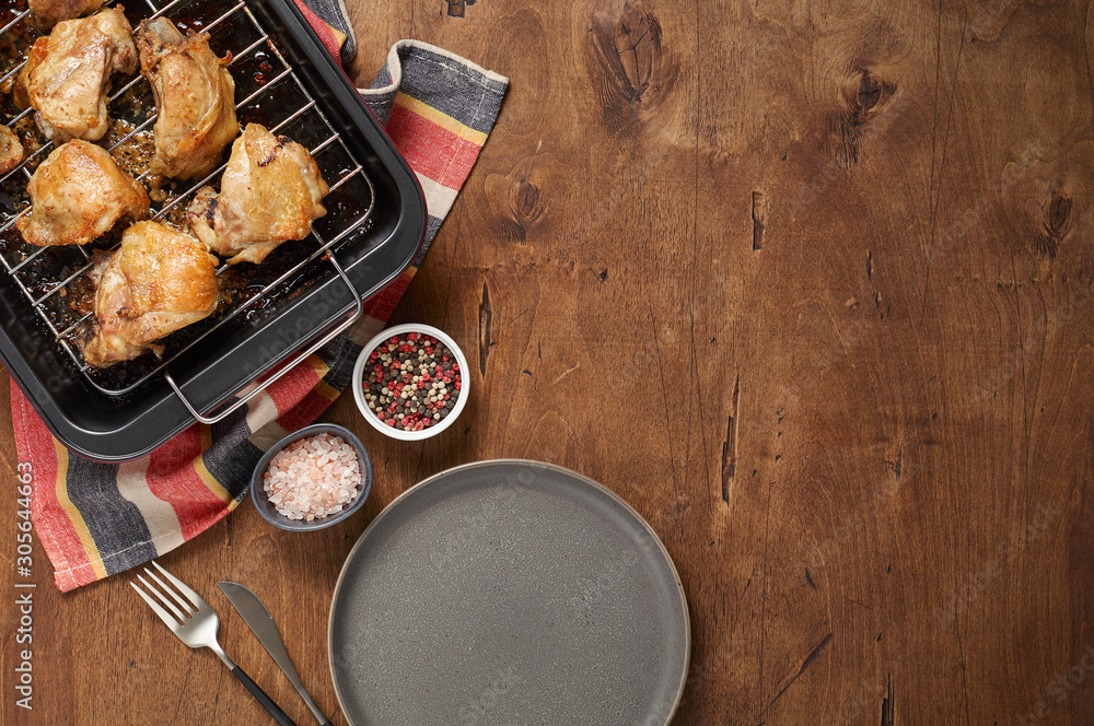 Garlic roast chicken in oven on wooden background