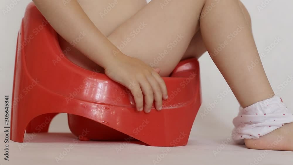 Little girl sits on a red pot. Accustoming to a toilet of children, background, hygiene Stock ビデオ | Adobe Stock 