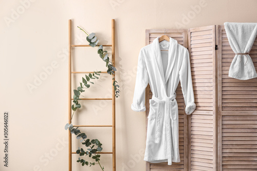 Soft comfortable bathrobe hanging on folding screen in stylish room interior photo
