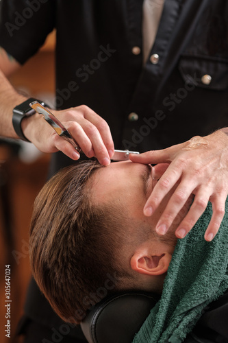 a barber shaves a man with a beard with a dangerous blade. 