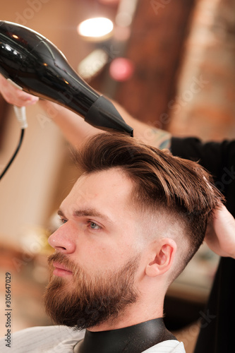 Fashionable man with a beard makes hair styling