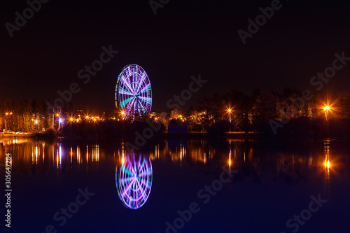 Illuminated observation wheel at night reflected in water