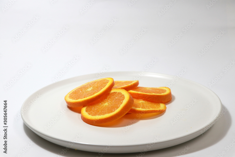The thin round pieces of orange slices put together on the white dish. The thin round pieces of orange slices put together on the white dish.