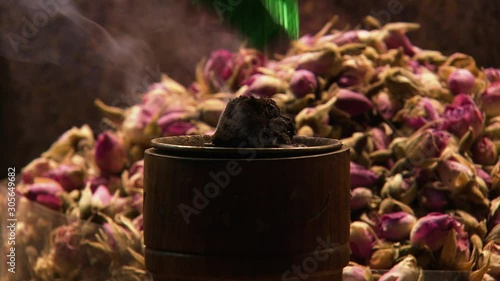 Close-up low angle still shot of burning incense in front of dried rose-flowers at a spice market. Spice Souk, Dubai, UAE photo