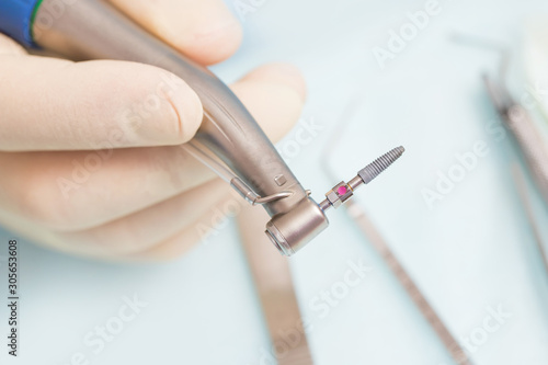 During the operation  the dentist holds implantation tools with a titanium implant