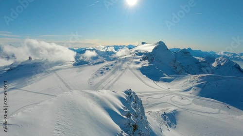 Aerial fpv fast descent over snow-caped alpine summit ridge towards ski slopes on Tsanfleuron glacier. Winter alpine scenery, Les Diablerets ski resort, Switzerland photo