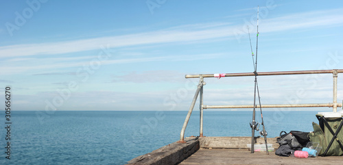 fishing paraphernalia sitting on the jetty and fishing rods resting on the rails waiting for a fish on a sunny afternoon, Victoria, Australia © fieldofvision