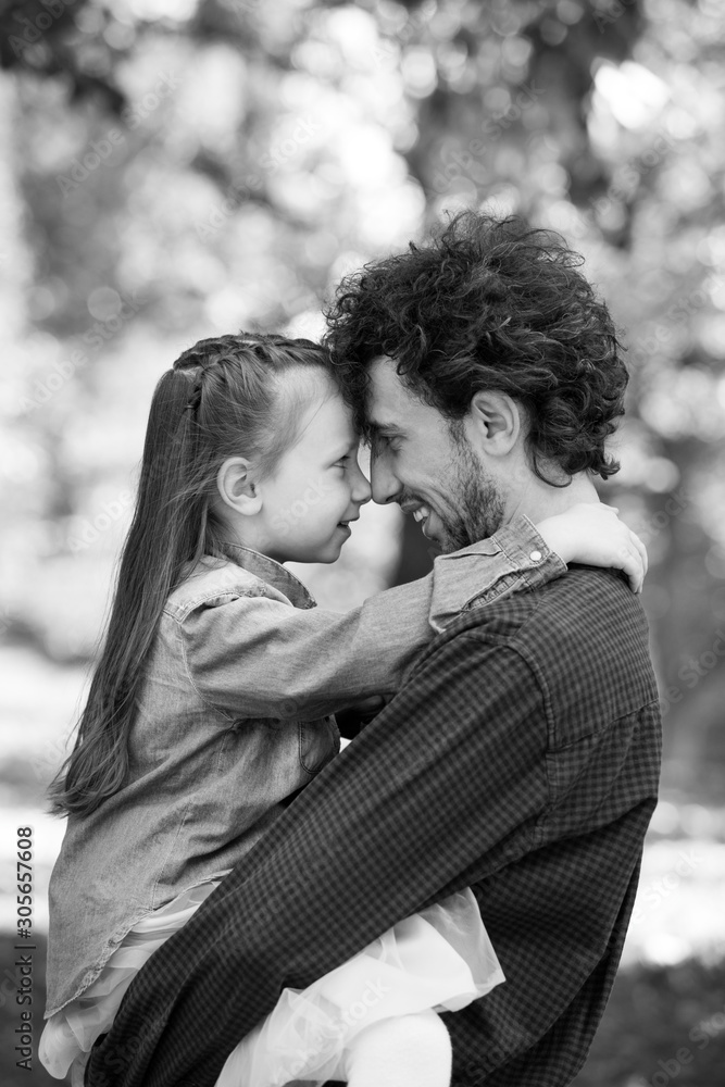 Fototapeta premium Family life. Portrait of dad and daughter in the Park. They pressed their foreheads together.