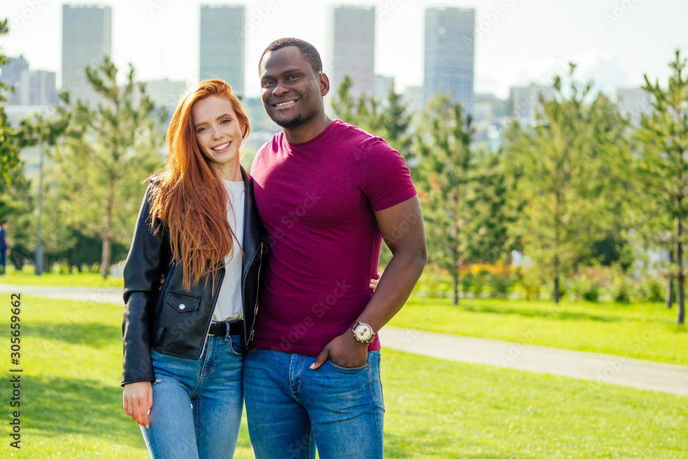 Portrait of young man hugging his girlfriend standing together on a spring summer park on a sunny day Portrait of young man hugging his girlfriend standing together on a spring summer park on a sunny day