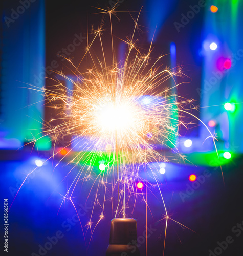 New year party burning sparkler closeup in blue background. Christmas light.