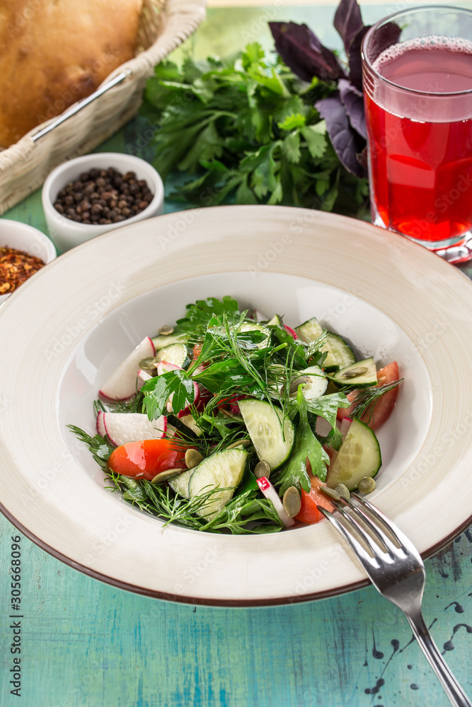 Plate of healthy green garden salad with radish, tomato and cucumber on blue wooden table Plate of healthy green garden salad with radish, tomato and cucumber on blue wooden table