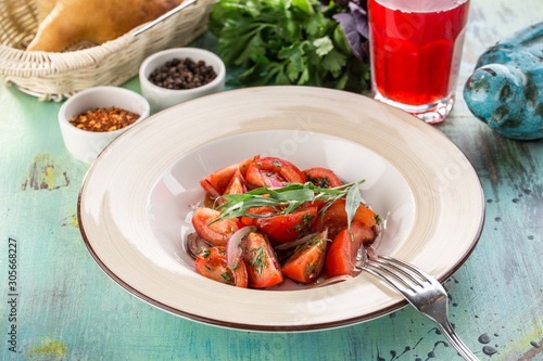 Fototapeta Naklejka Na Ścianę i Meble -  healthy appetizer fresh tomato salad in white bowl with red onion and estragon on blue wooden table