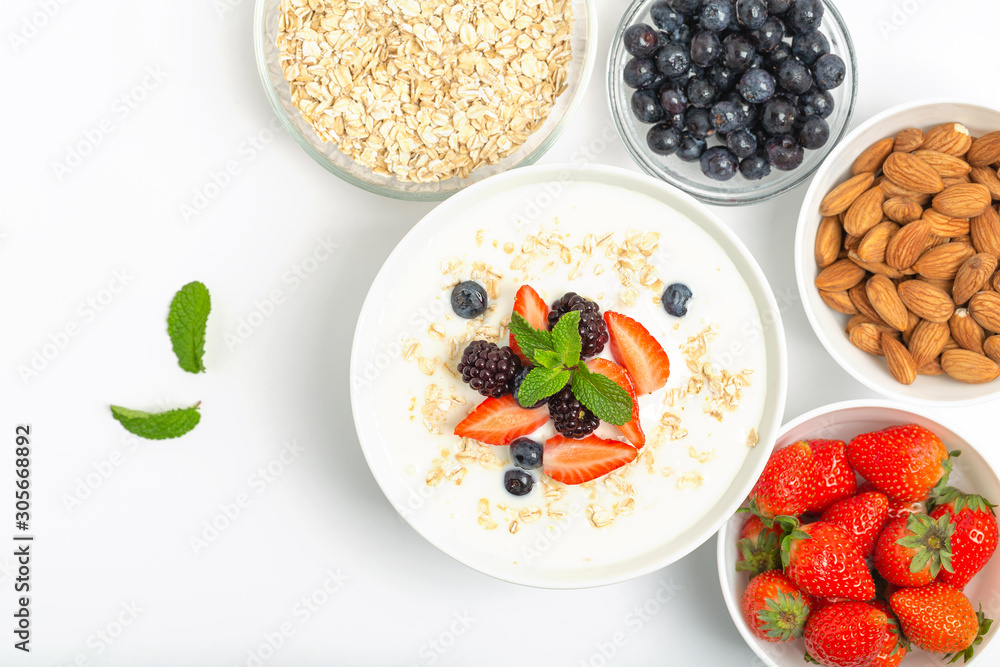 Greek yogurt with granola fresh strawberries, blueberries, blackberries and almonds on white table. Healthy snack. Breakfast food. Top view, copy space. Greek yogurt with granola fresh strawberries, blueberries, blackberries and almonds on white table. Healthy snack. Breakfast food. Top view, copy space.