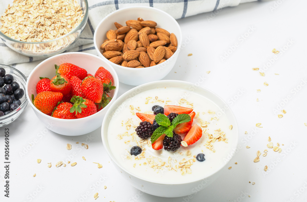 Greek yogurt with granola fresh strawberries, blueberries, blackberries and almonds on white table. Healthy snack. Breakfast food. Greek yogurt with granola fresh strawberries, blueberries, blackberries and almonds on white table. Healthy snack. Breakfast food.