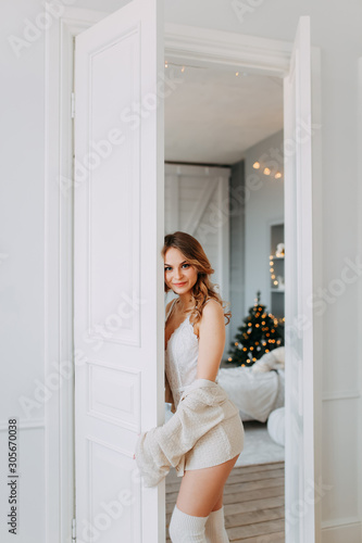 Young beautiful happy girl with blonde hair in home cozy clothes waiting for the new year and magic