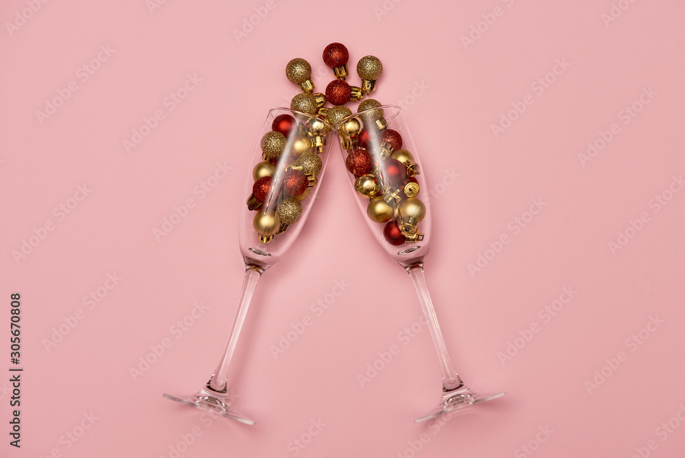 Champagne glasses with golden and red baubles on pastel pink background, copy space. Minimal, New year concept. Top view, flat lay Champagne glasses with golden and red baubles on pastel pink background, copy space. Minimal, New year concept. Top view, flat lay