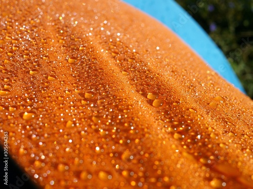 Photo of orange waterproof fabric covered with numerous water drops. Orange background with drops of water.