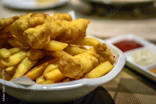 fried fish and chips with tomato ketchup, tartar sauce and mustard sauce on the side