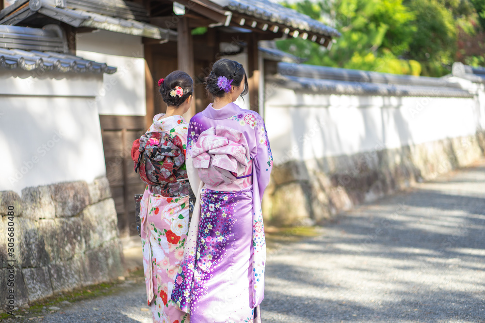 Geishas girl wearing Japanese kimono among red wooden Tori Gate at Fushimi Inari Shrine in Kyoto, Kimono is a Japanese traditional garment. The word 