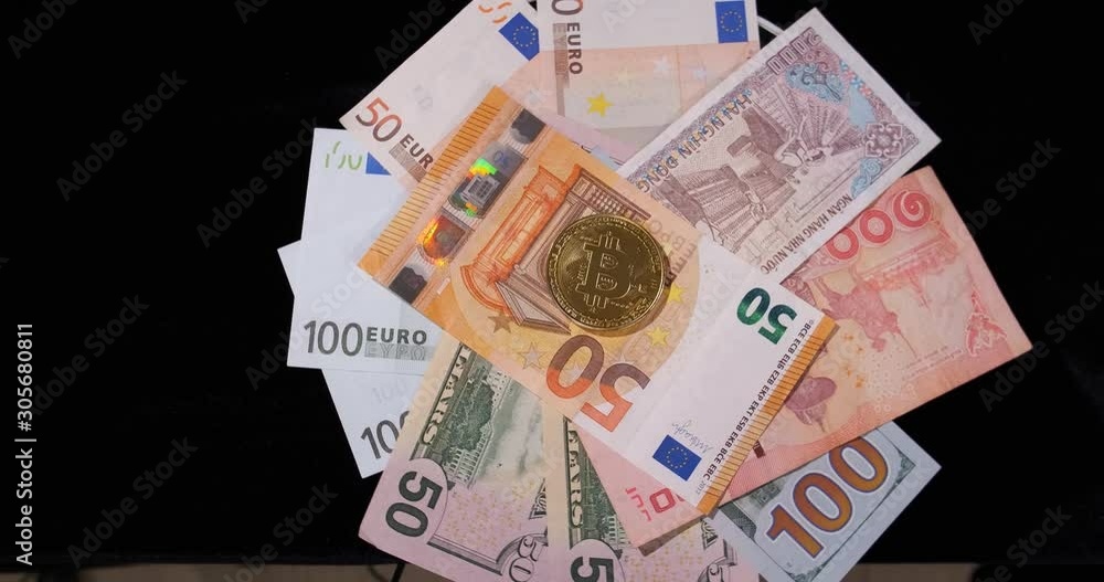 On rotating black surface are banknotes of different countries, United States, European Union, dollars, euros, coin with bitcoin symbol, gold coin, fiat money exchange,coin falling in center of frame On rotating black surface are banknotes of different countries, United States, European Union, dollars, euros, coin with bitcoin symbol, gold coin, fiat money exchange,coin falling in center of frame