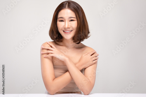 Beautiful Young Asian Woman with short hairs Touching Shoulder feeling so happy and cheerful with healthy Clean and Fresh skin,isolated on gray background,Beauty Cosmetology Concept