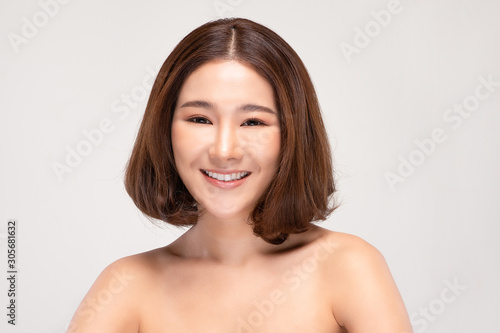 Beautiful Asian woman with short hairs looking at camera smile with clean and fresh skin Happiness and cheerful with positive emotional isolated on gray background Beauty and Cosmetics Concept