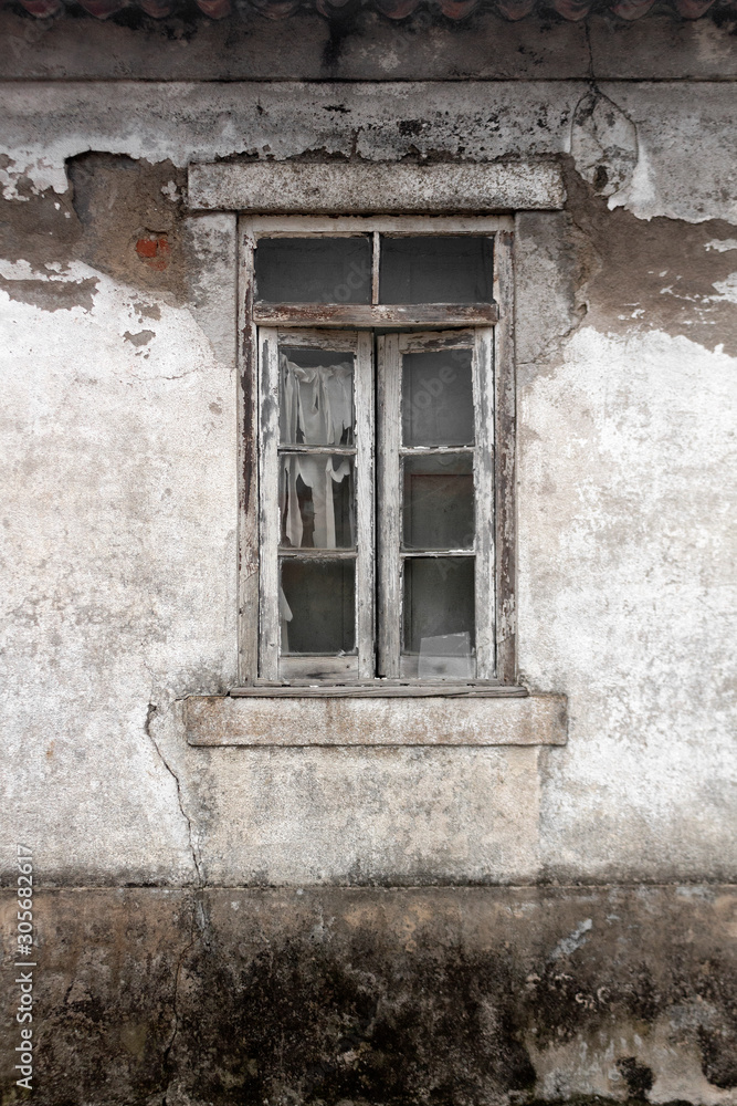 Window with rotten wood frame and broken glass on derelict building with plaster coming off a white wall with red bricks underneath. Decay. Background. Game scenario textures. Grunge