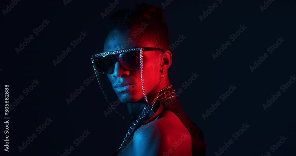 Rear view of African man turning around wearing chain necklace and fancy goggles in ultraviolet light Rear view of African man turning around wearing chain necklace and fancy goggles in ultraviolet light