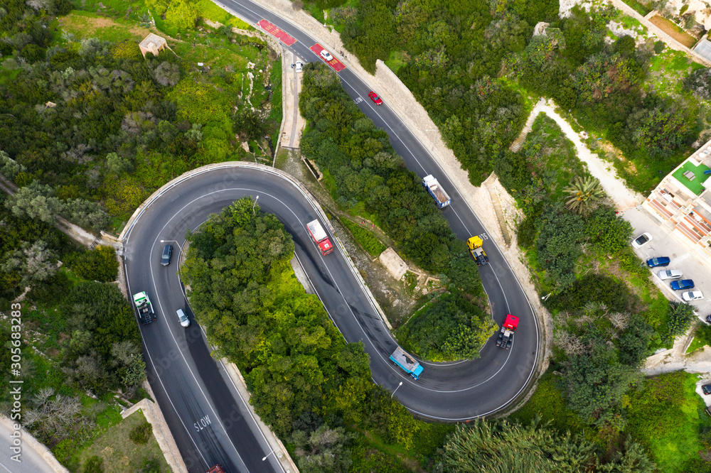 Cars on the curves road in Mellieha city. Top aerial view. Malta country