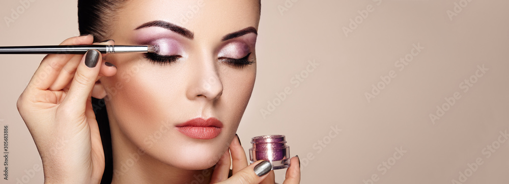 Makeup artist applies eye shadow. Beautiful woman face. Perfect makeup. Makeup detail. Beauty girl with perfect skin. Nails and manicure - obrazy, fototapety, plakaty 